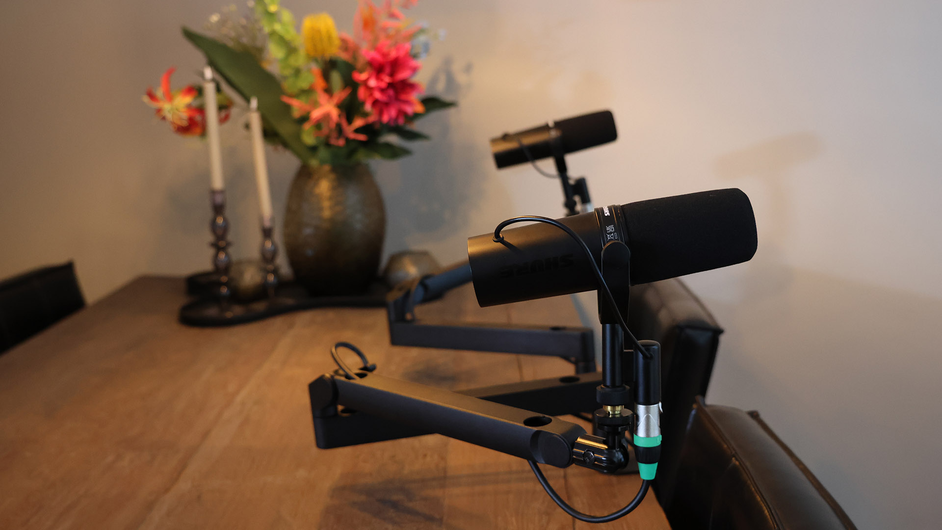 Twee Shure-microfoons op zwenkarmen aan de houten keukentafel in de studio